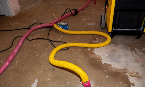 water extraction setup with hoses and pump removing standing water from concrete floor