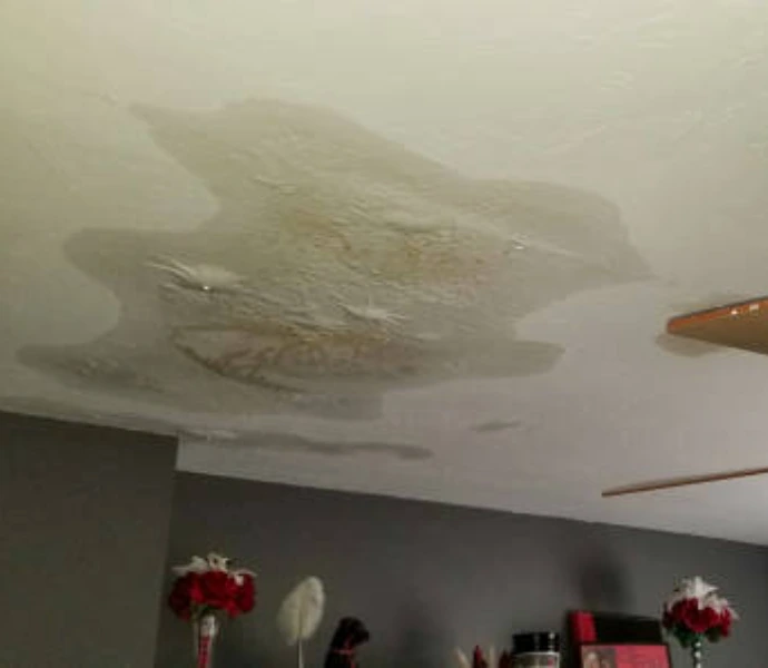 Severely water-damaged ceiling with large bubbling, peeling, and stained sections caused by an active roof or plumbing leak requiring immediate water damage restoration