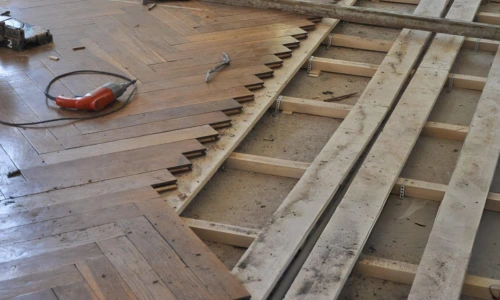 hardwood floor water damage repair with removed planks exposing subfloor and joists