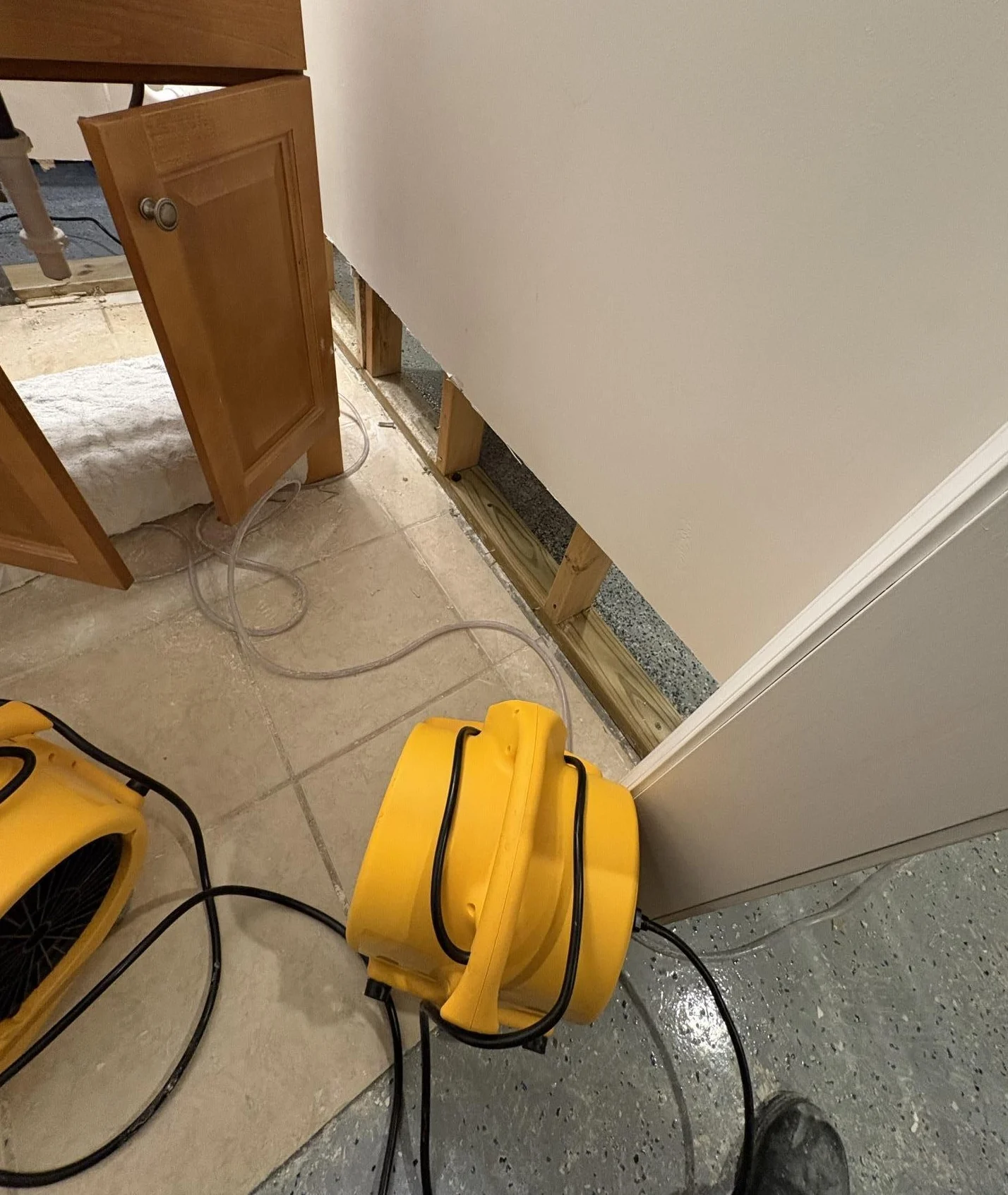 water damage drying with baseboard removed and air mover drying wall cavity and subfloor