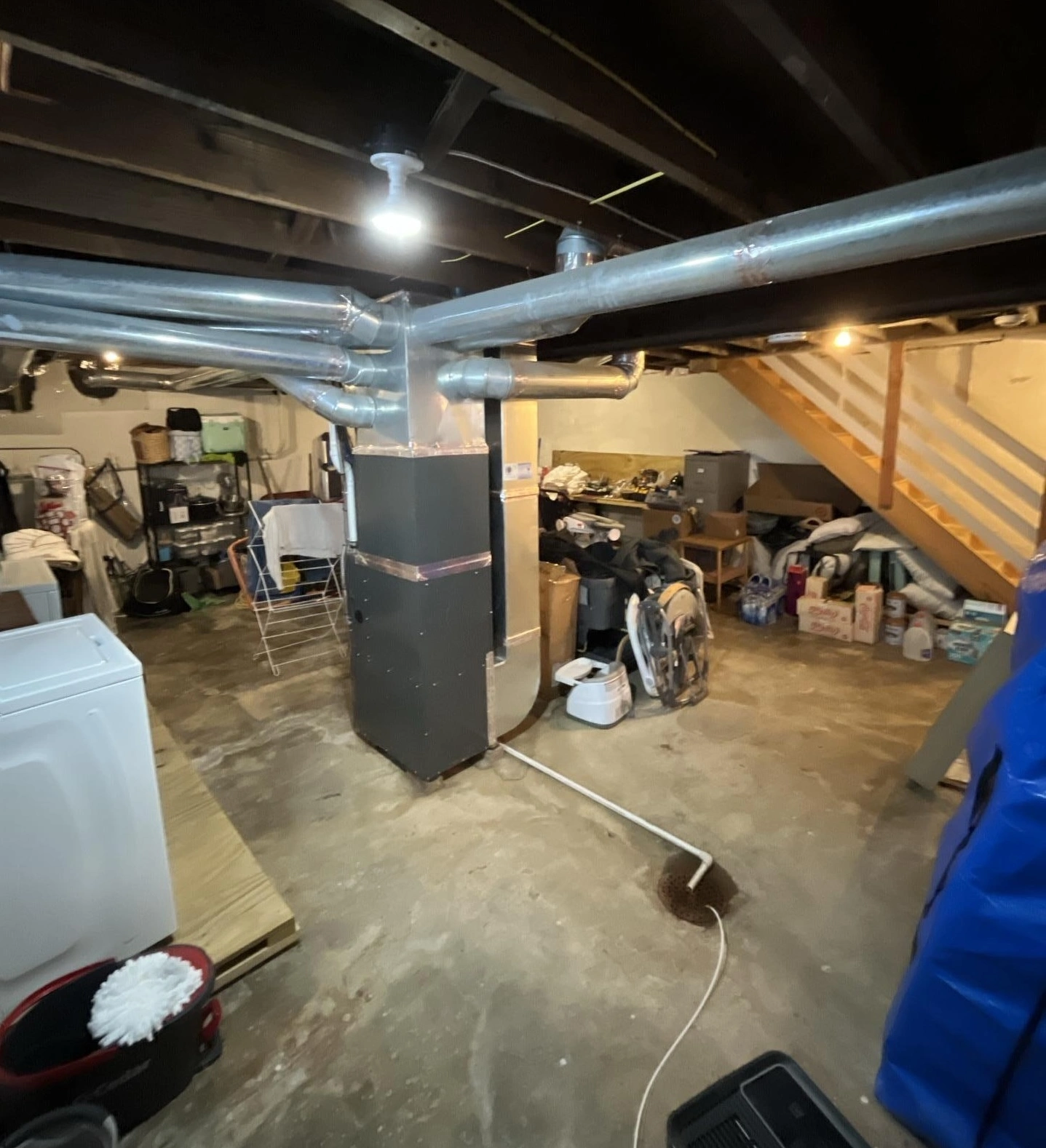 basement water damage with standing water around HVAC system and floor drain after flooding