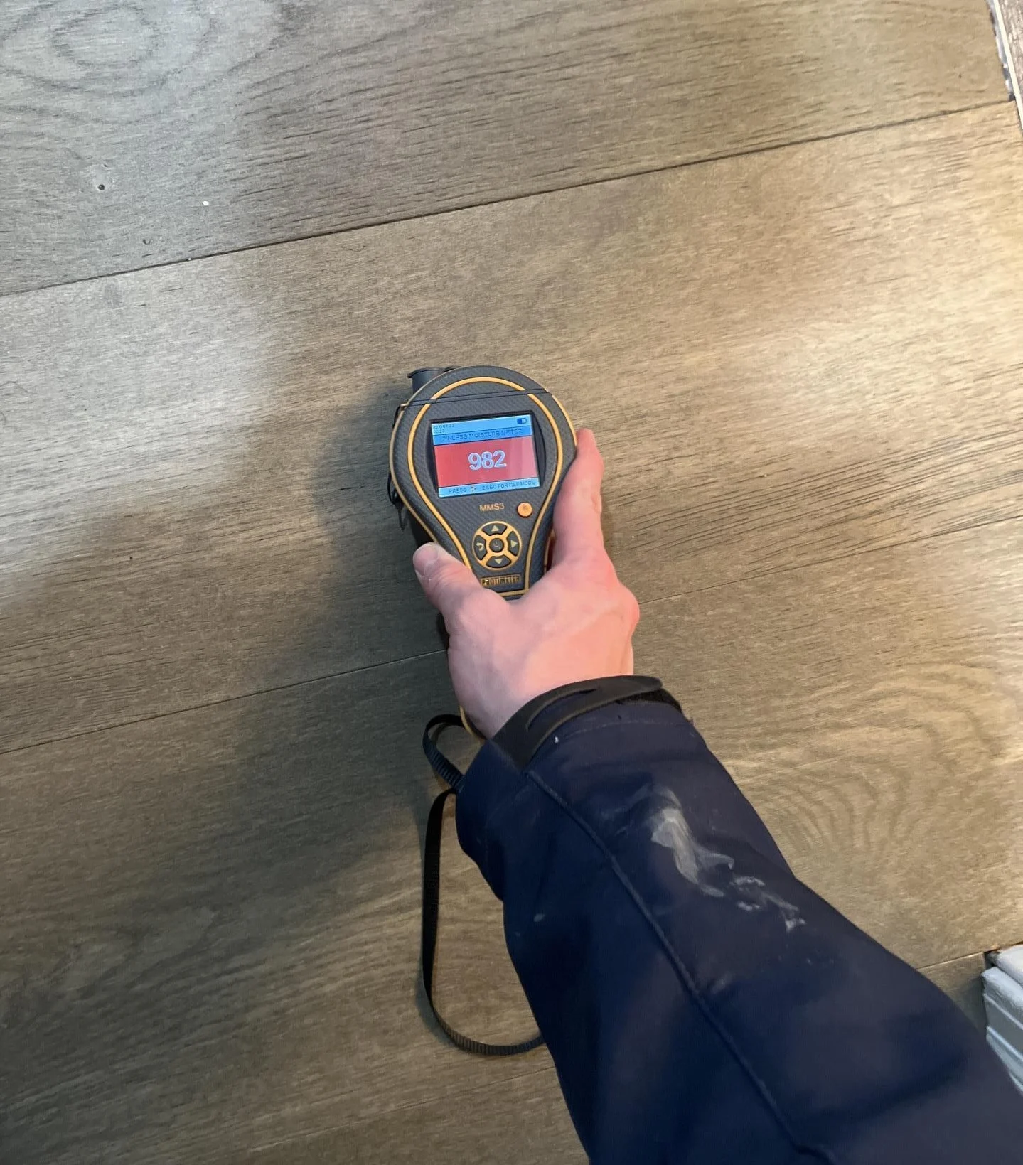 moisture meter reading high moisture levels in hardwood floor after water damage