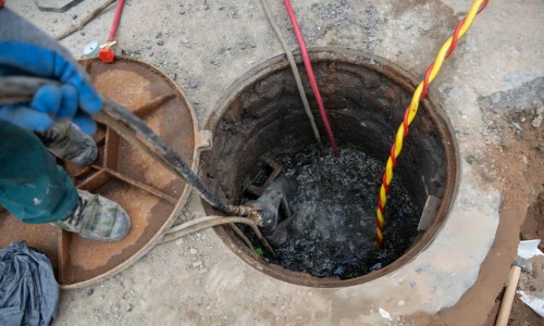 sewage pump cleaning manhole with hoses removing wastewater during cleanup
