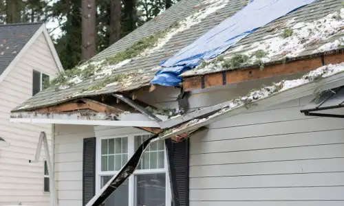 roof storm damage with missing shingles and exposed structure causing water intrusion